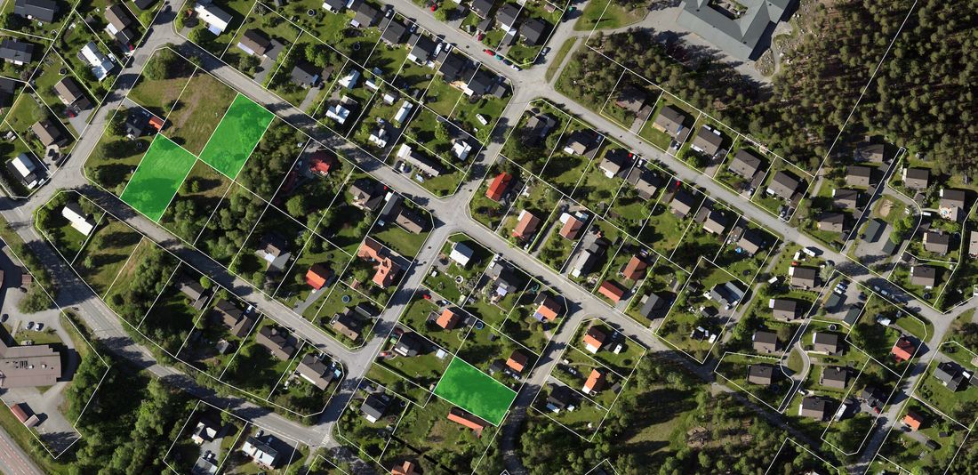 Övergripande flygbild över ett bostadsområde med obebyggda tomter och utritade tomtgränser